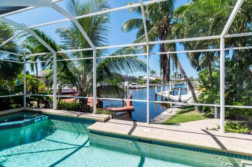 a pool with a view of the water and palm trees at Perfect Blend of Elegance and Comfort I Captivating Home For Idyllic Retreat in Marco Island
