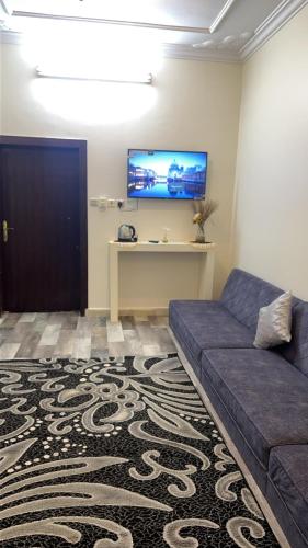 sala de estar con sofá y TV en la pared en غرفه en Hail
