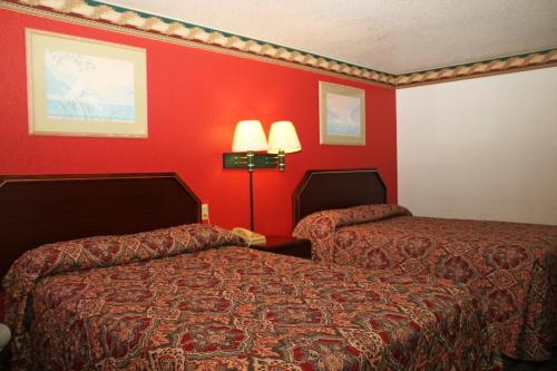 a hotel room with two beds and red walls at Lone Star Inn Llano in Llano