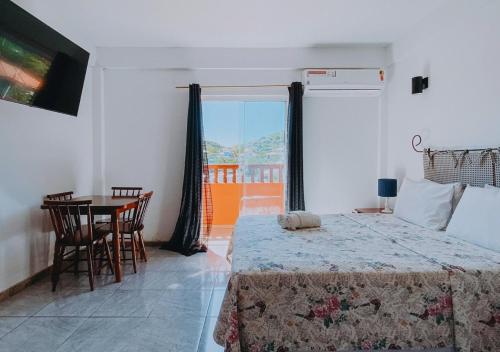 a bedroom with a bed and a table and a window at Calador Búzios Hotel in Búzios