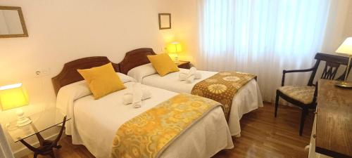una camera d'albergo con due letti con cuscini gialli di La casa de la plaza a Cudillero