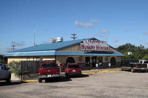 a car dealership with cars parked in a parking lot at Lone Star Inn Llano in Llano