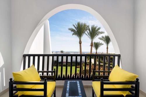 a balcony with two chairs and palm trees at Hilton Marsa Alam Nubian Resort in Abu Dabab