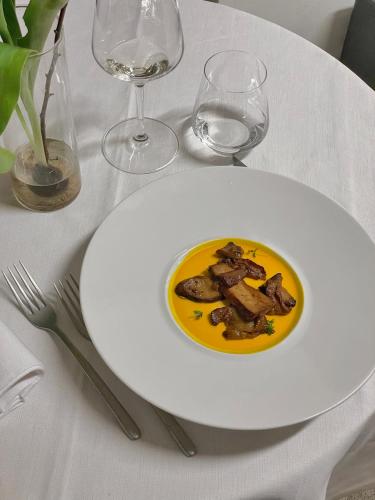 a plate of food on a table with wine glasses at Hotel Villa Policreti in Castello dʼAviano