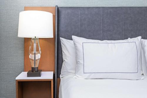 a bed with a white pillow and a lamp on a night stand at DoubleTree by Hilton Tulsa - Warren Place in Tulsa
