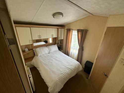 a small bedroom with a white bed in it at 6 Berth Static Caravan, Golden Palm Resort, Chapel St Leonard's in Chapel Saint Leonards
