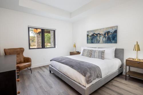 een witte slaapkamer met een bed en een stoel bij Suncadia Trailhead 2 Pet Friendly Condo 109 in Cle Elum