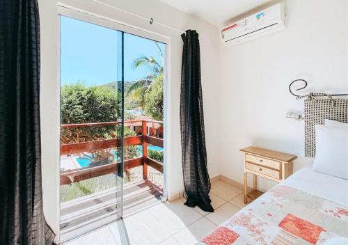 a bedroom with a bed and a large window at Calador Búzios Hotel in Búzios