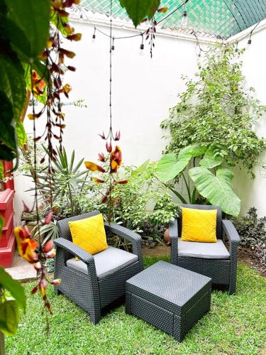 two wicker chairs with yellow pillows in a garden at Casa Balam Bed & Breakfast Boutique in Ciudad Vieja