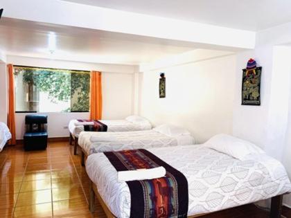 Cette chambre comprend 3 lits. dans l'établissement Tierra Mágica Hostal, à Machu Picchu