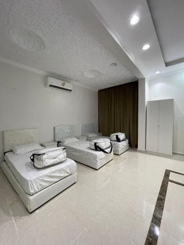 3 Betten in einem großen Zimmer mit weißen Wänden in der Unterkunft شاليه الفوز 2 in Medina