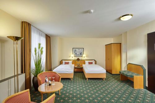 Cette chambre d'hôtel comprend deux lits, une table et des chaises. dans l'établissement Balance Hotel Leipzig Alte Messe, à Leipzig