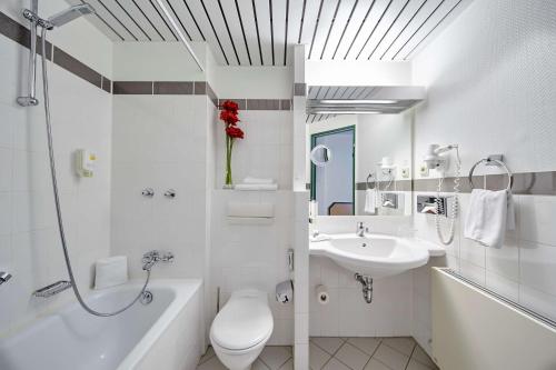 a white bathroom with a toilet and a sink at Balance Hotel Leipzig Alte Messe in Leipzig