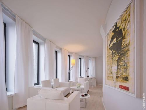 a living room with white furniture and a painting on the wall at Dorint Kurfürstendamm Berlin in Berlin