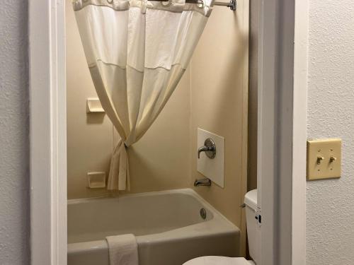 a bathroom with a white tub and a shower curtain at Motel 6 Montgomery, AL - Eastern Blvd. in Montgomery