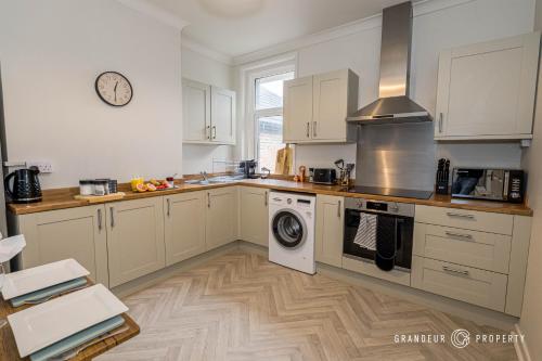 uma cozinha com armários brancos e uma máquina de lavar e secar roupa em New! Stylish 2 bed flat with parking near beach - Parkstone Central em Parkstone