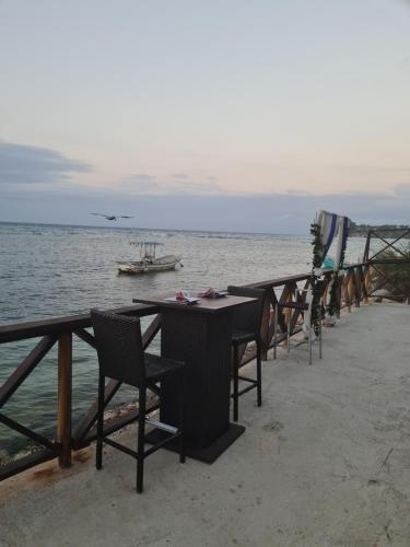 a row of tables and chairs next to the water at Sky Beach Rooms in Lucea