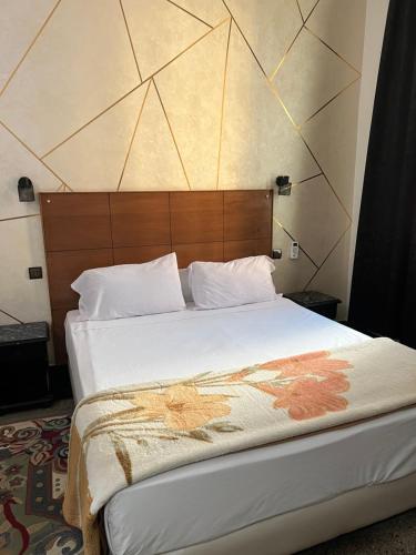 een slaapkamer met een groot bed met een houten hoofdeinde bij Amor Hotel in Fès