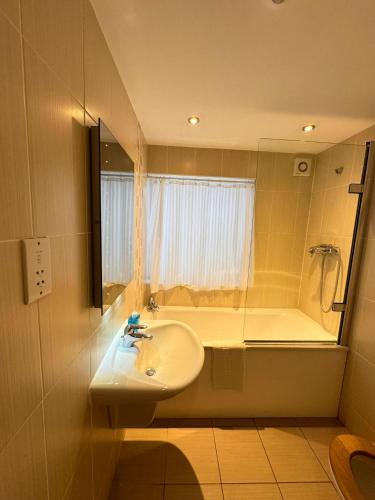 a bathroom with a sink and a tub with a mirror at Villare Hitchin Town Centre in Hitchin