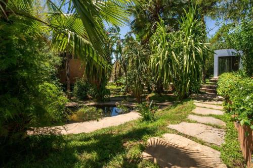 a garden with a pond and palm trees at Hotel Molino Garden in Chefchaouene