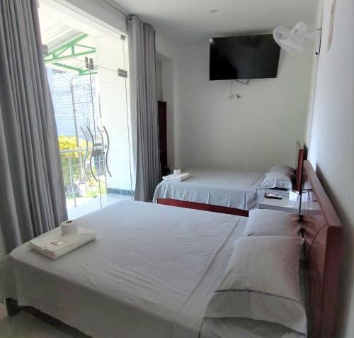 a bedroom with two beds and a tv on the wall at Hospedaje Vista Paraíso in Tingo María