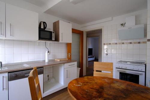 cocina con mesa de madera y cocina con electrodomésticos blancos en Apartment Scholl- Eutingen-Pforzheim, en Pforzheim