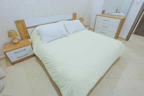 ein Schlafzimmer mit einem großen weißen Bett und zwei Nachttischen in der Unterkunft 3 bed Akid Lotfi with parking in Bir el Djir