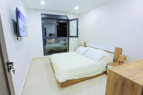 Schlafzimmer mit einem Bett, einem TV und einem Fenster in der Unterkunft 3 bed Akid Lotfi with parking in Bir el Djir