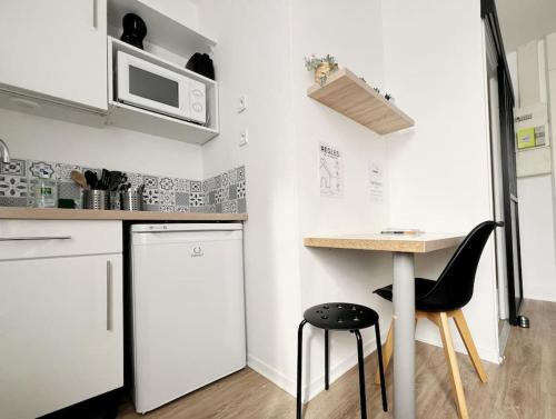 a small kitchen with a table and a microwave at Alger Lodge in Nantes