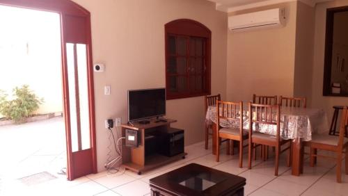 uma sala de estar com uma televisão e uma mesa e cadeiras em Sobrado na Praia do Laranjal em Pelotas
