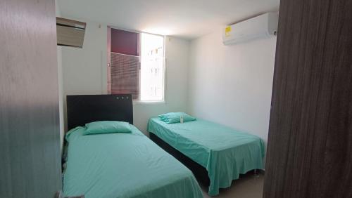 Habitación con 2 camas y ventana en Bello Apto Zona Norte, Cerca al Malecon en Barranquilla