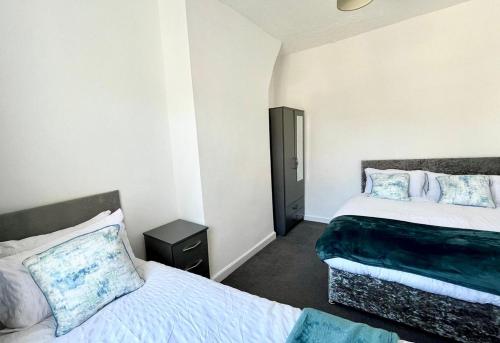 a bedroom with two beds and a black cabinet at Crystal House- Liverpool City in Litherland