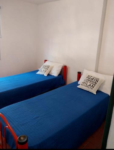 two beds in a room with blue sheets and white pillows at Tu casita de paso 2 in General Acha