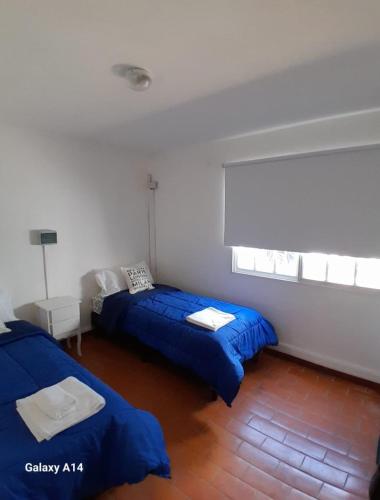 two beds in a room with blue sheets at Tu casita de paso 2 in General Acha