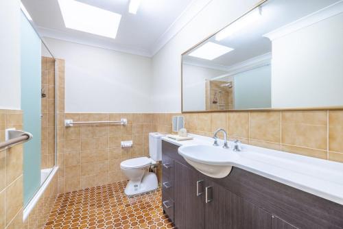 a bathroom with a sink and a toilet and a mirror at The Dunes 17 38 Marine Drive fabulous unit with pool tennis court in Fingal Bay