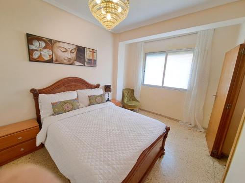 a bedroom with a bed and a window and a chandelier at Apartamento exterior de tres habitaciones in Valencia