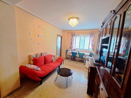 a living room with a red couch and a clock on the wall at Apartamento exterior de tres habitaciones in Valencia