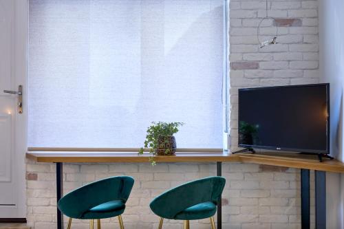 a living room with two green chairs and a television at Acropolis 2BD Private Entrance Apt in Athens
