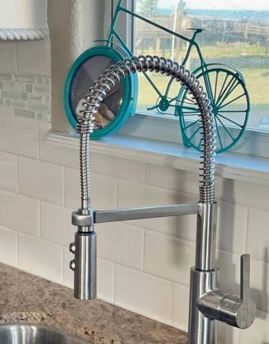 a kitchen sink with a faucet with a bike in a window at Private beach access -360 Water Views - Upscale home - Second Row in Surfside Beach
