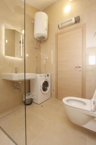 a bathroom with a toilet and a sink and a washing machine at Apartman Mimoza in Budva