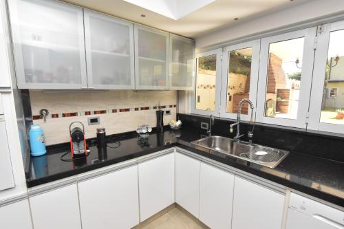 a kitchen with white cabinets and a sink and windows at Casa Relax in Roque Sáenz Peña