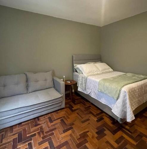 a bedroom with a bed and a couch at Loft aconchegante no Menino Deus in Porto Alegre