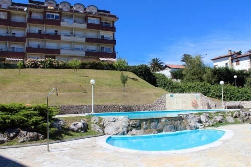 a swimming pool in front of a building at Apartamentos Acacio in Suances