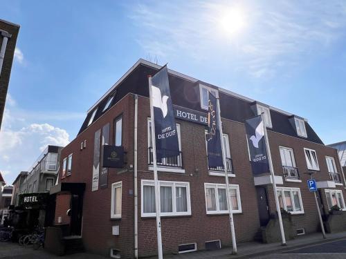 a brick building with flags in front of it at Hotel de Duif Lisse - Keukenhof in Lisse