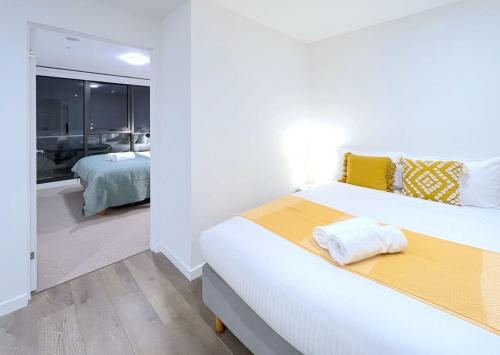 a white bedroom with a large bed and a bathroom at Pride Moonee Ponds 1B2B Nest in Melbourne