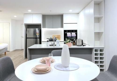 a white kitchen with a table and chairs at Pride Moonee Ponds 1B2B Nest in Melbourne