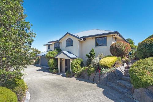 a house with a driveway with bushes and trees at Jacaranda - Views over Tasman Bay in Nelson