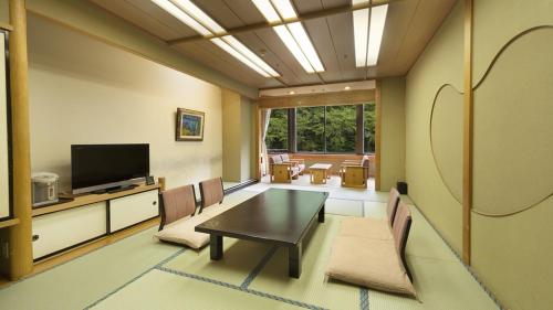 a living room with a table and chairs and a television at Minakami Hotel Juraku in Minakami