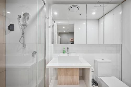 a white bathroom with a sink and a shower at Boutique 1 Bedroom Apartment, Central location in Brisbane