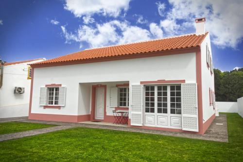 a small white house with a green lawn at Casa do Norte (AL) in Biscoitos